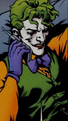 the joker is talking on his cellphone while wearing green and yellow clothes, with one hand up to his ear