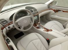 the interior of a car with all white leather and wood trims, including steering wheel