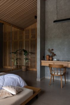 a bed sitting in a bedroom next to a wooden desk and plant on top of it