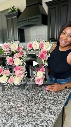 a woman standing in front of a counter with flowers on it and the letter d spelled out