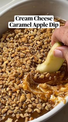 a person is dipping an apple into some kind of food in a bowl with nuts