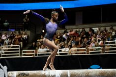 a woman is standing on the balance beam in front of an audience