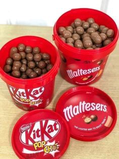 three red buckets filled with chocolate covered candies on top of a wooden table