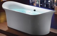 a white bath tub sitting on top of a wooden floor next to a window with city lights in the background