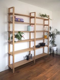 a wooden shelf with plants and books on it