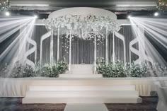 the stage is decorated with white flowers and chandeliers for an elegant wedding ceremony