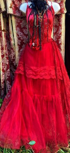 a mannequin wearing a red dress in front of a wall with floral decorations