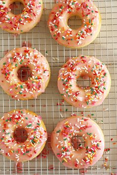 six glazed donuts with sprinkles on a cooling rack