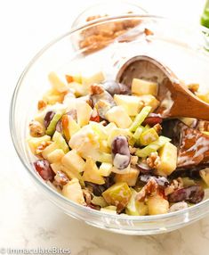 a glass bowl filled with fruit and nuts next to another bowl full of salad ingredients