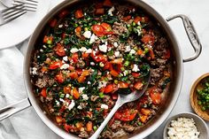 a pot filled with meat and vegetables next to two bowls full of rice, spoons and utensils