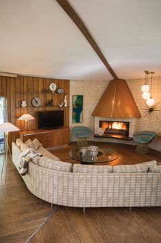 a living room with a fire place in the center and couches around it on top of hard wood flooring