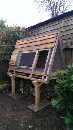 a chicken coop built into the side of a wooden fenced in area next to a house