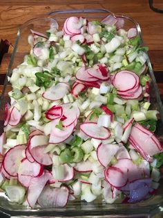 a glass dish filled with radishes and other vegetables