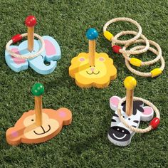 four wooden toys on the grass with ropes and rings around them, including zebra, giraffe, monkey