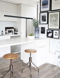 two stools in front of a kitchen island with pictures on the wall above it