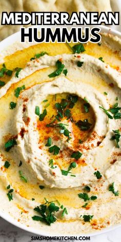 hummus in a white bowl with herbs on top