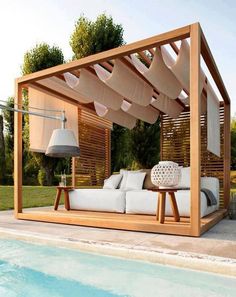 a bed sitting next to a swimming pool under a wooden pergolan roof with white pillows on it