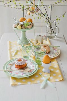 an easter table setting with eggs and cupcakes