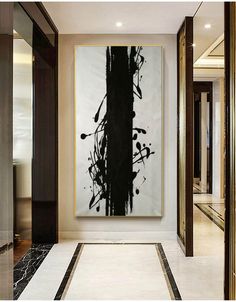 an abstract painting hangs on the wall next to a hallway with marble floors and walls