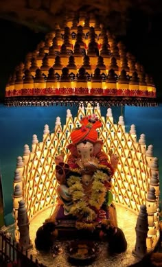 an idol is displayed in front of a lit up temple with lights on the roof