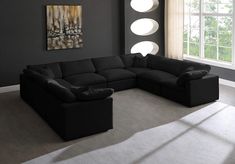 a living room with a large black sectional couch in front of a painting on the wall