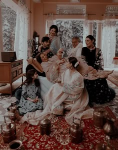 a group of women sitting on top of a red rug in front of a window