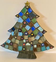 a decorative glass christmas tree on a white table with blue and green tiles in the shape of a star