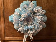 a close up of a wreath on a door with blue and white ribbons hanging from it