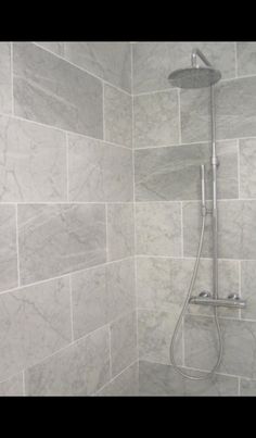 a shower head in a bathroom with grey marble tiles on the walls and flooring