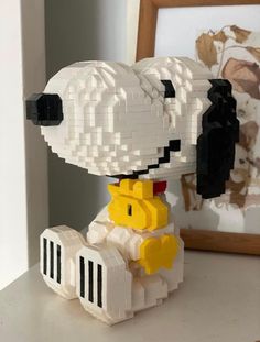 a lego dog sitting on top of a white table next to a framed photo in a frame