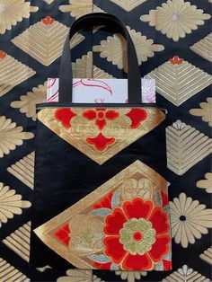 a black bag with gold and red designs on it's side, sitting on a patterned surface