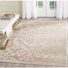 a beige and white rug with an intricate design on the floor in front of a window