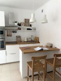 a kitchen with white cabinets and wooden chairs