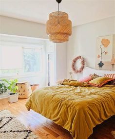 a bedroom with a bed, rugs and plants on the floor in front of a window