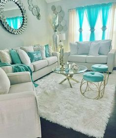 a living room filled with white furniture and blue curtains