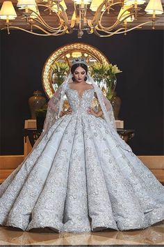 a woman in a white wedding dress standing next to a chandelier with lights on it