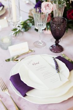 the table is set with purple and white place settings