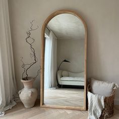 a large mirror sitting on top of a wooden floor next to a vase and pillow