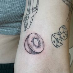 a tattoo on the arm of a woman with dices and kiwi in it