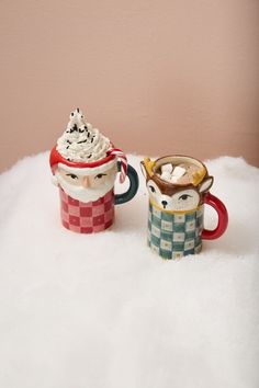 two coffee mugs sitting on top of a pile of white fluffy material next to each other