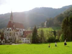 two people and a child are running in a field with a church in the background