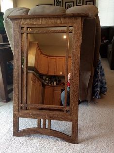 a mirror sitting on the floor in front of a couch with a person looking at it