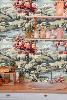 a kitchen with a wallpaper that has trees and flowers on it in the background