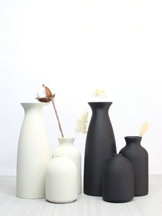 three black and white vases sitting next to each other on top of a table