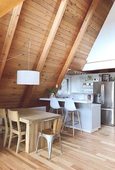 a kitchen and dining area in an attic with wooden floors, white walls and ceiling