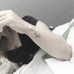 a woman with a bow tattoo on her left arm and right arm behind her head