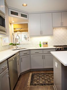 a kitchen with gray cabinets and white counter tops is seen in this image from the doorway