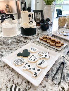 a table topped with cookies and desserts on top of a marble countertop next to a cake