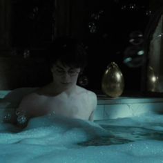 a man sitting in a bathtub with bubbles around him