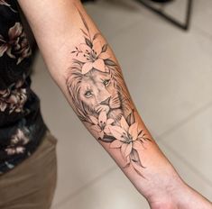 a woman's arm with a lion and flowers on it